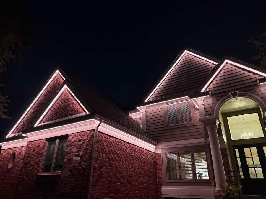 Two-story home with gable peaks lit in warm white